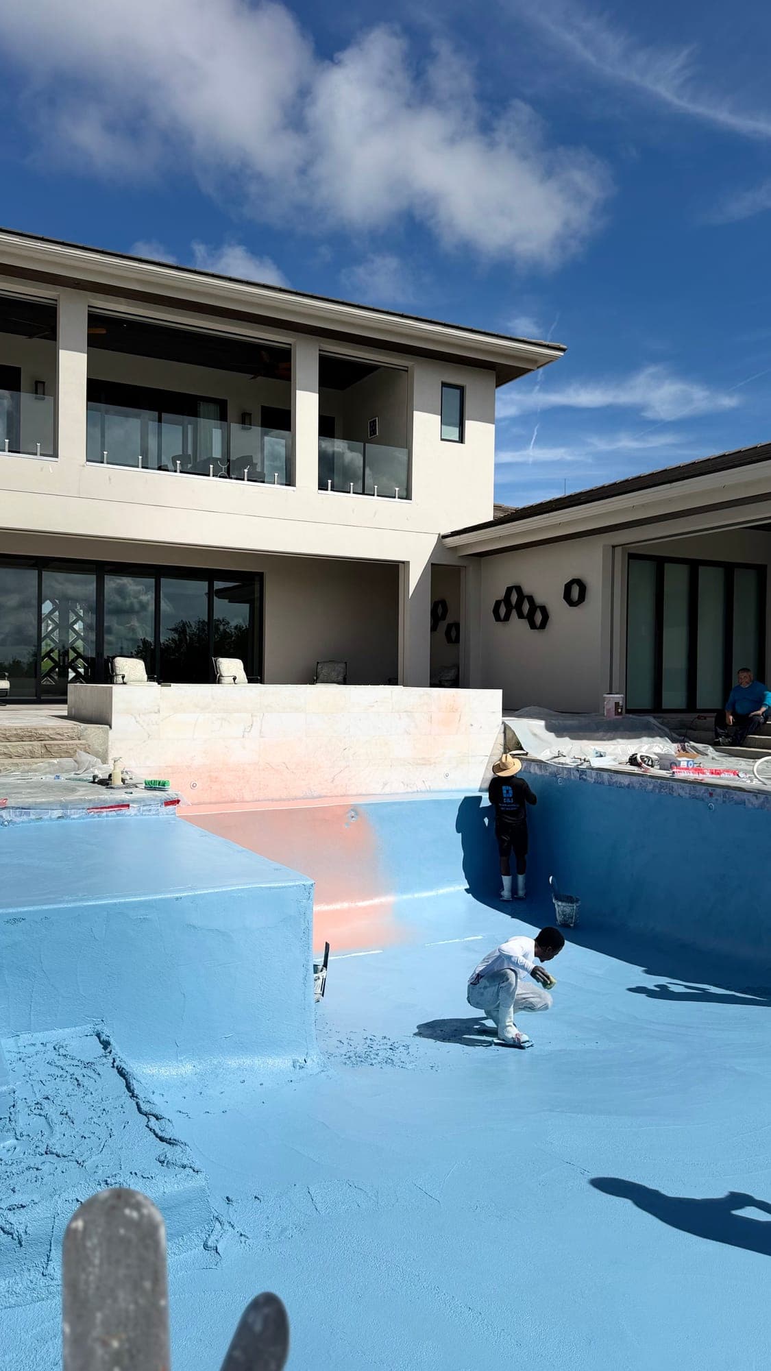 D&J crew member working inside a drained pool behind a two-story home