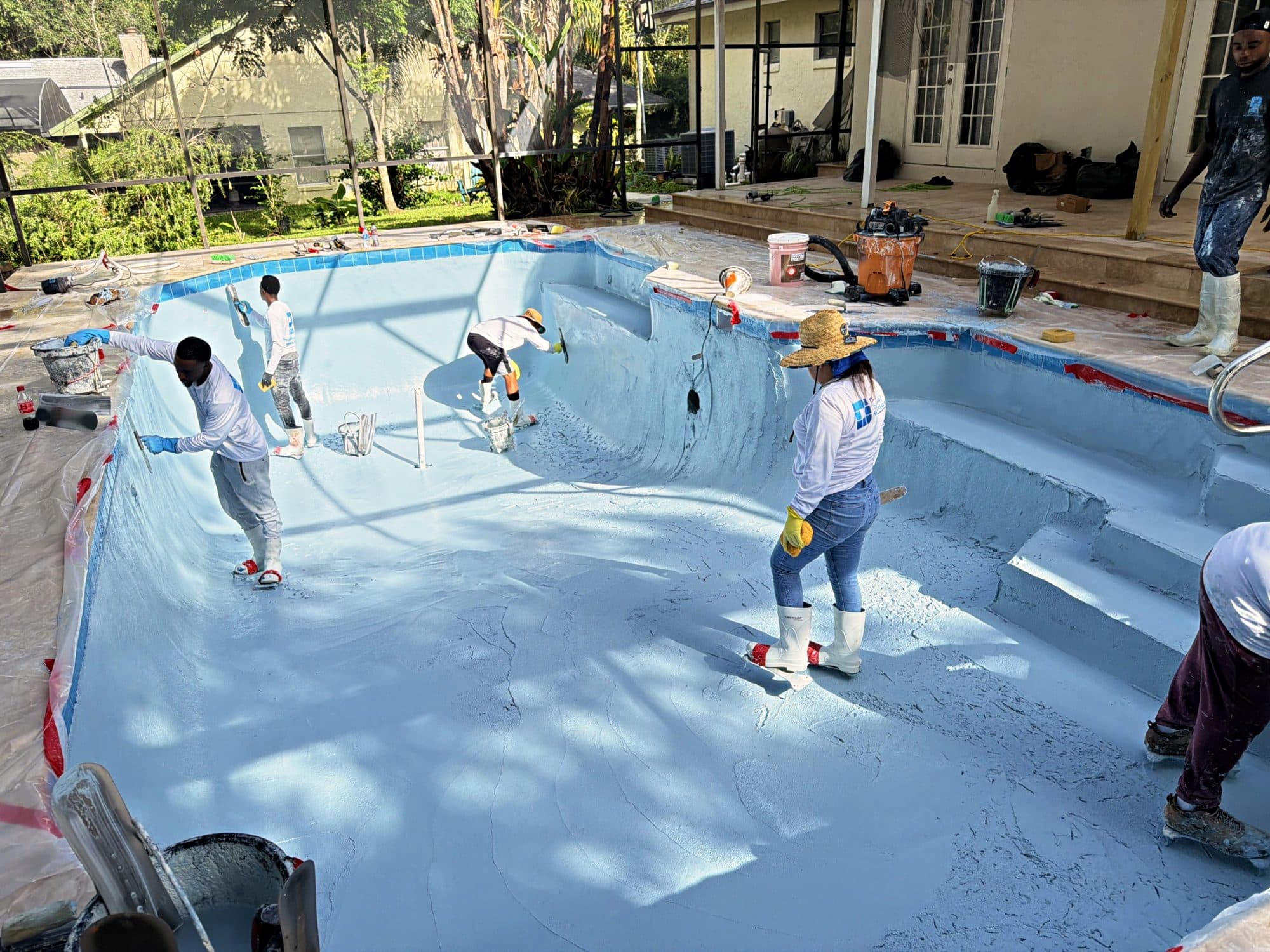 Crew spreading the new finish across a pool floor