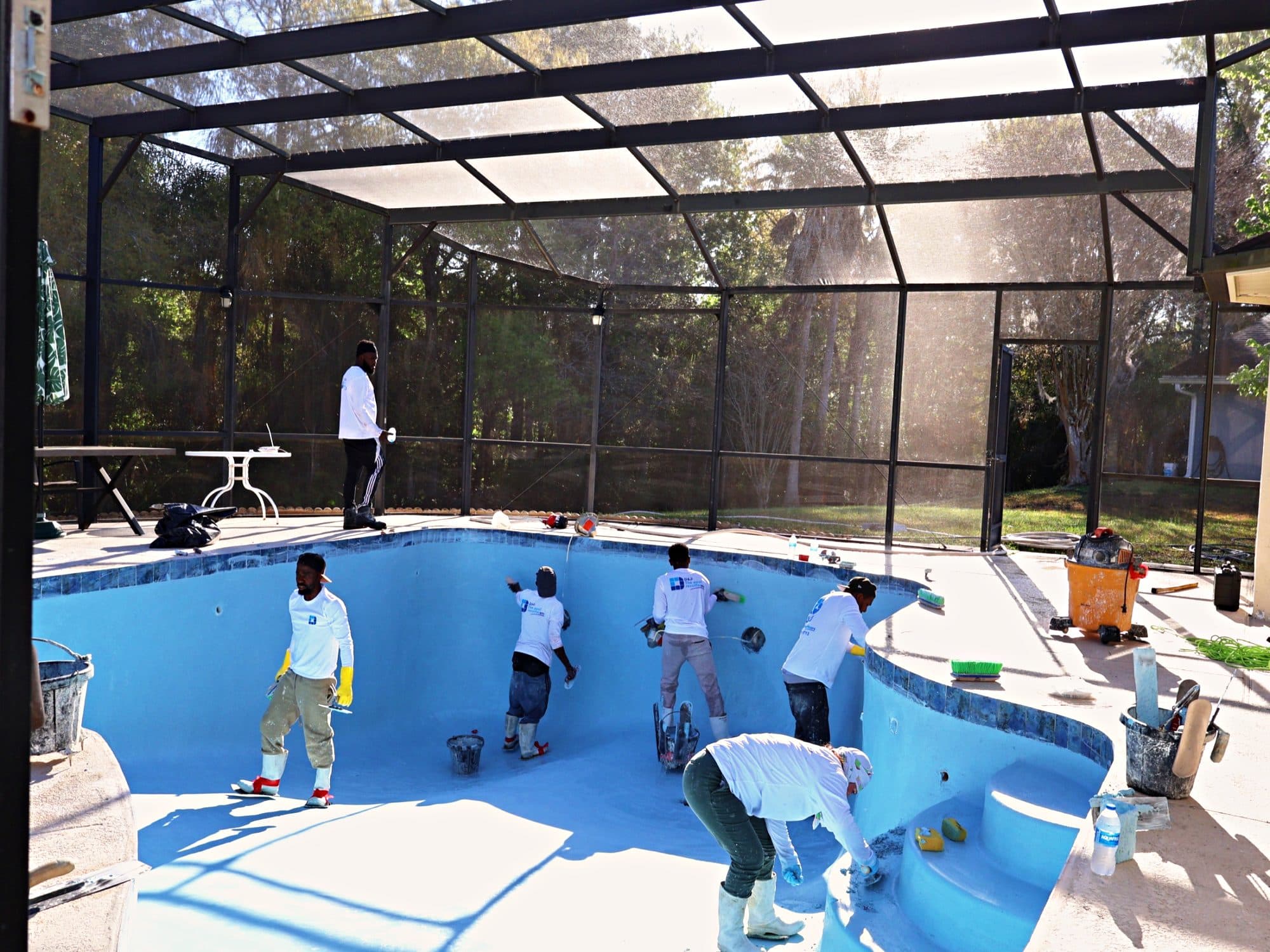Crew finishing a pool under a screen enclosure