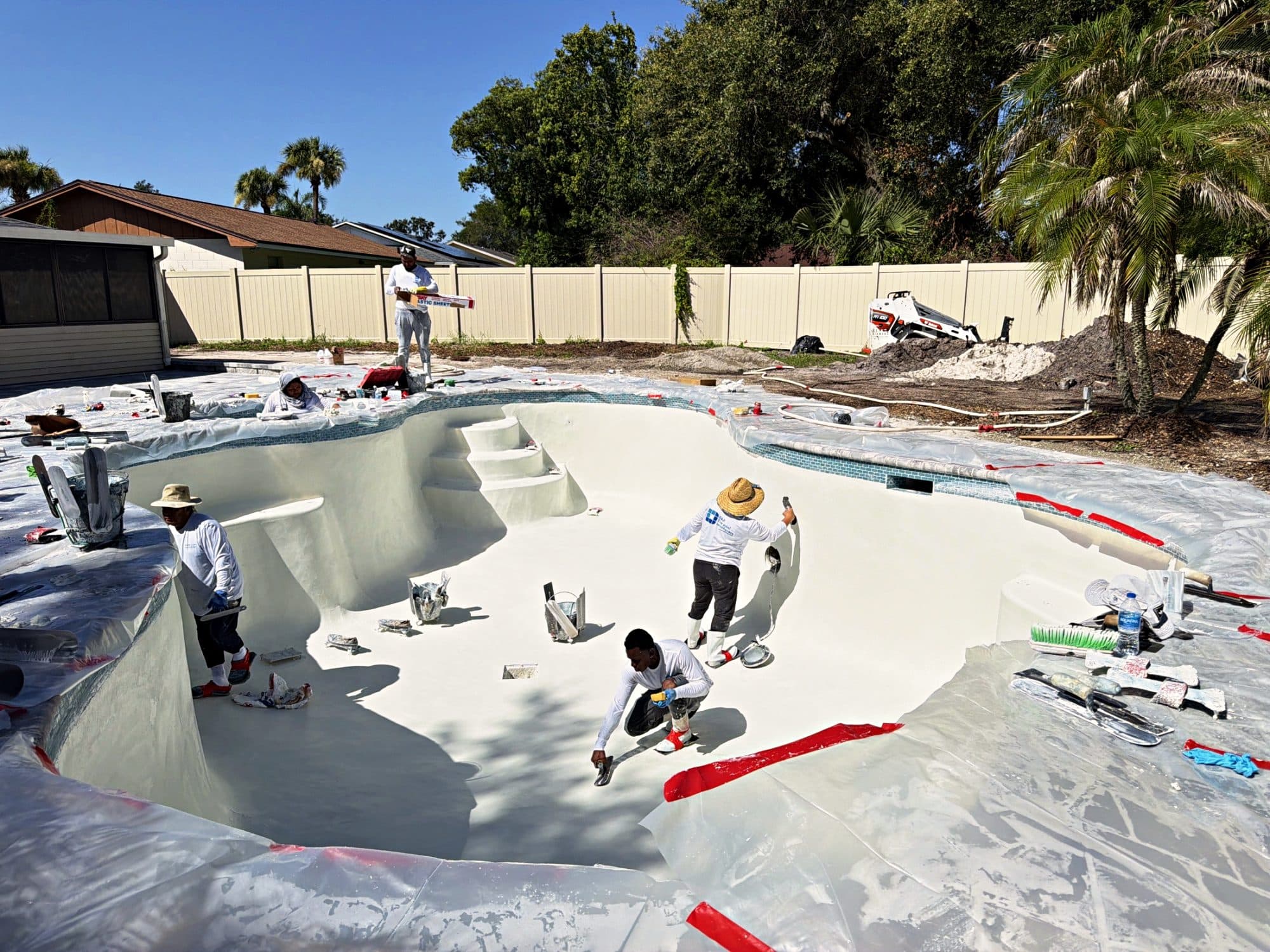 Crew finishing a pool with a spa and steps